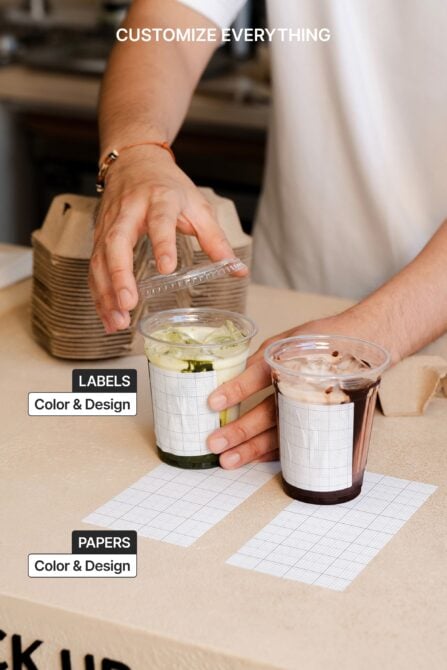 Two iced drinks with customizable label wraps shown on table with blank papers