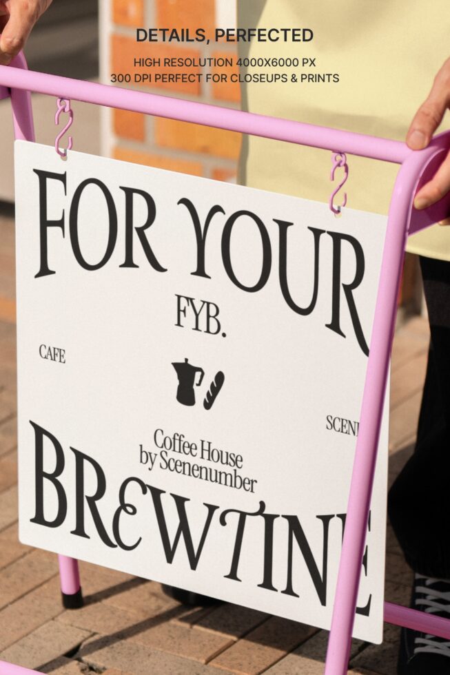 Hands holding vibrant pink sandwich board sign with white panel featuring coffee shop branding