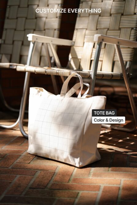 White canvas tote bag sitting on woven chair in sunlit scene