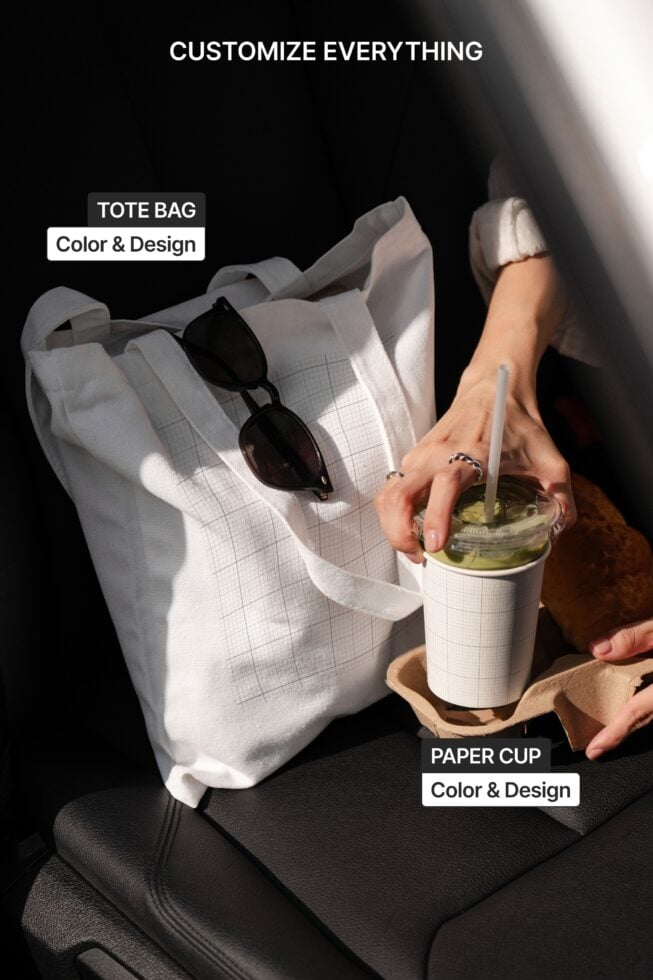 Styled product scene showing white tote bag with matching paper cup sunglasses on black leather surface