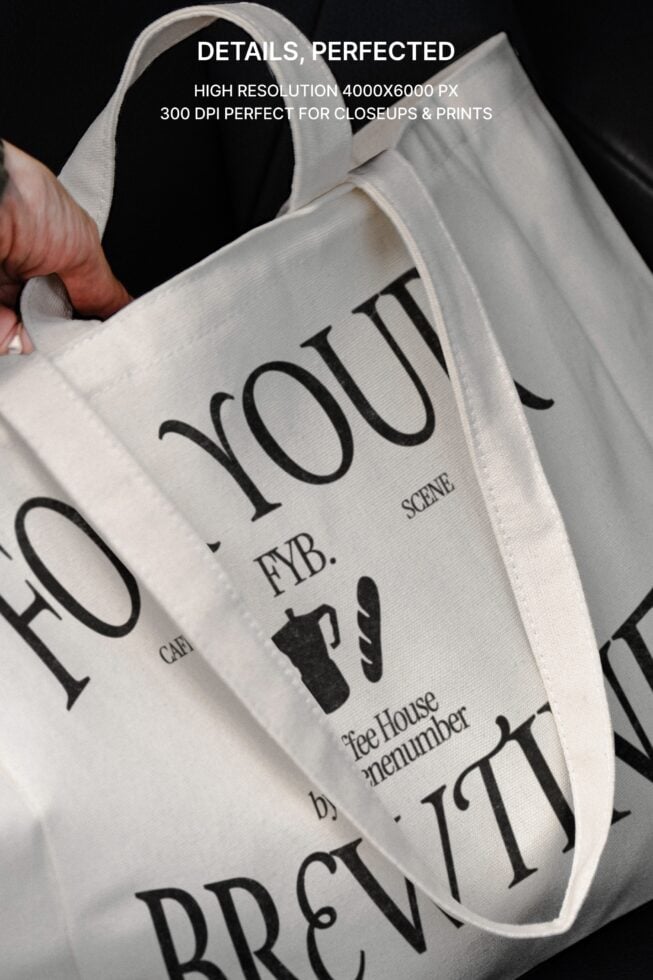 Close-up detail of white canvas tote showing typography texture seams against neutral background