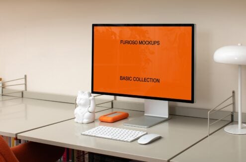 Desk workspace with monitor showing orange screen, accessories nearby