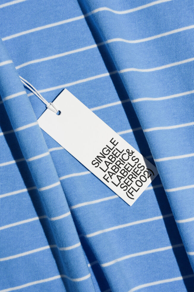 Clothing tag on light blue striped fabric with natural shadow overlay