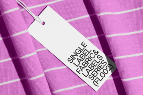 Clothing tag on vibrant pink striped fabric with natural shadow overlay