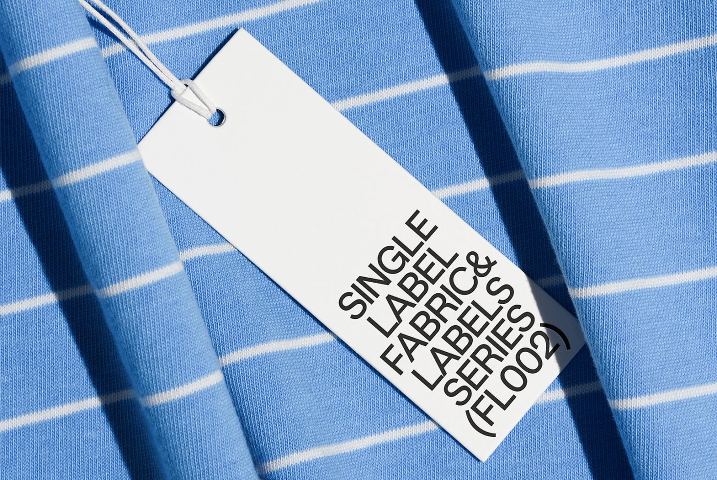 Clothing tag on light blue striped fabric with natural shadow overlay