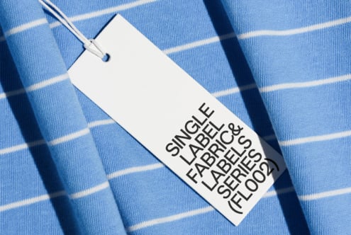 Clothing tag on light blue striped fabric with natural shadow overlay