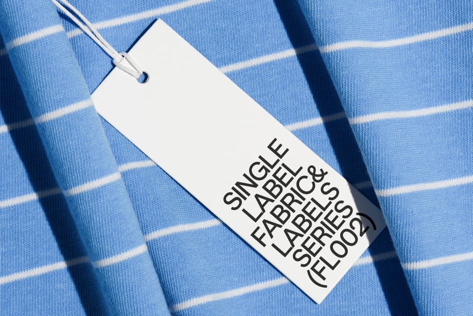 Clothing tag on light blue striped fabric with natural shadow overlay