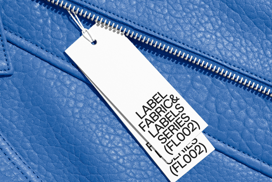 White fabric label on bright blue textured leather with metal zip detail