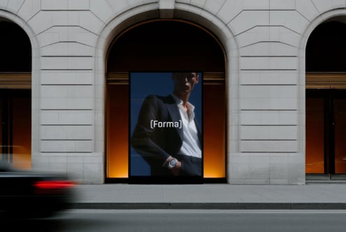 Storefront display with man in blazer on blue background, arched entryway with warm lighting