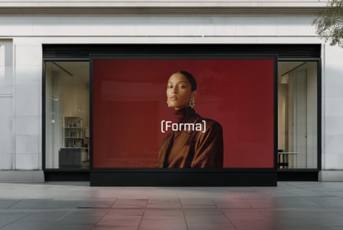 Modern storefront with woman in cream sweater posed against green foliage