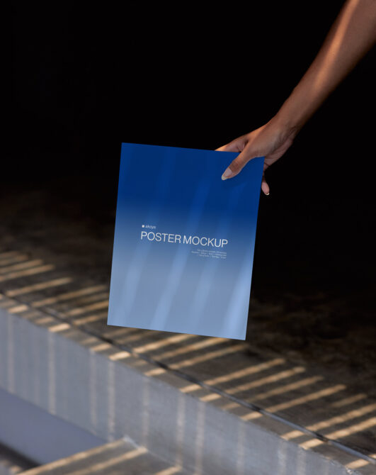 Hand holding blue gradient poster mockup against shadow-striped surface