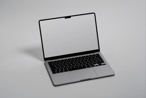 Silver macbook open with blank white screen on gray background