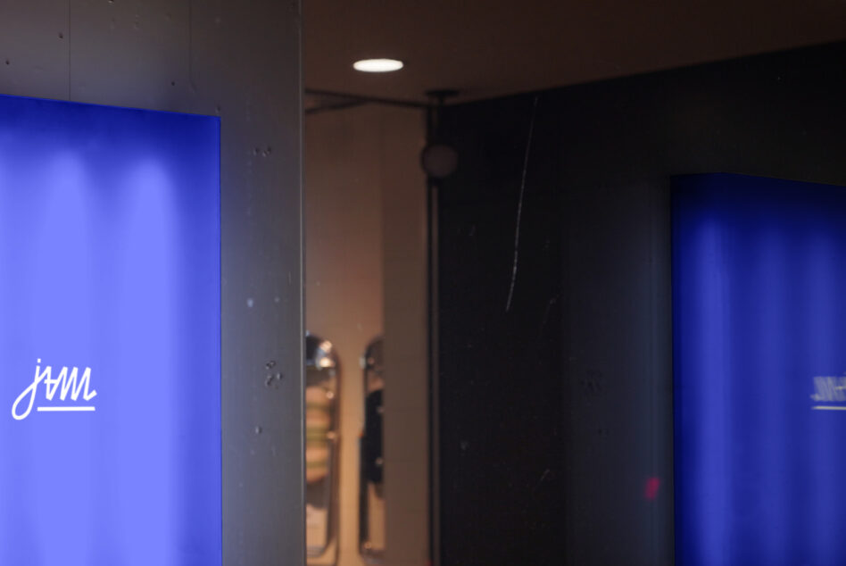 Bright blue vertical display panels with handwritten logo in concrete corridor space