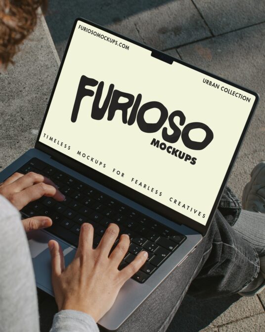 Laptop screen displaying cream background with black Furioso text, person typing