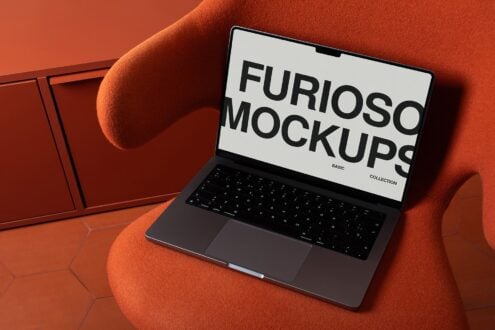 Laptop displaying white screen with large black sans serif type on orange fabric