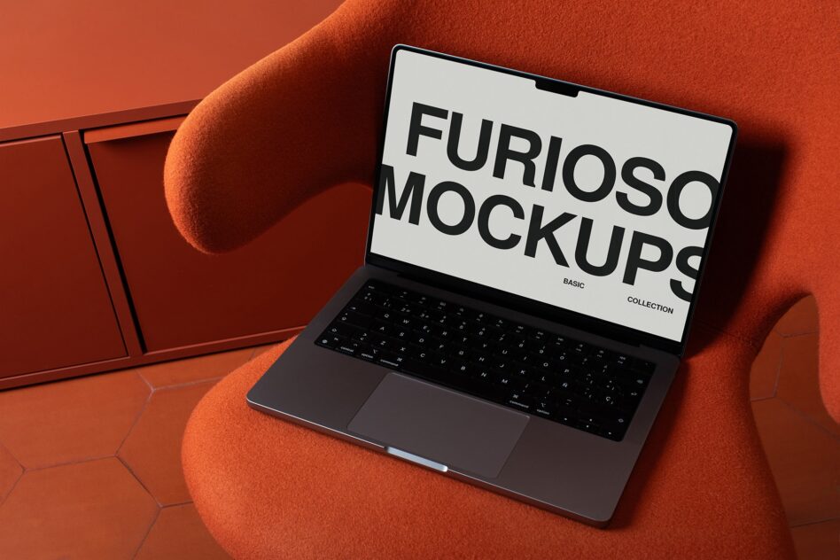 Laptop displaying white screen with large black sans serif type on orange fabric