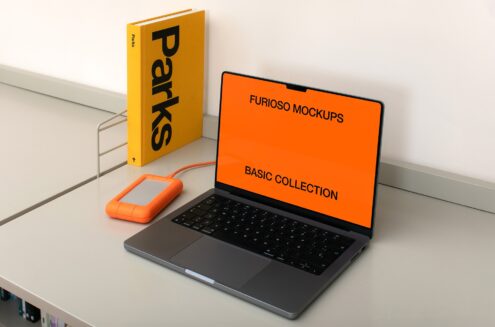 Desk scene with yellow Parks book, orange hard drive, laptop showing Furioso Mockups Basic