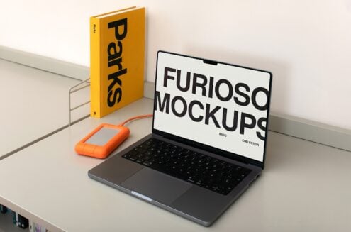 Workspace featuring yellow Parks book, orange external drive, laptop with white Furioso screen