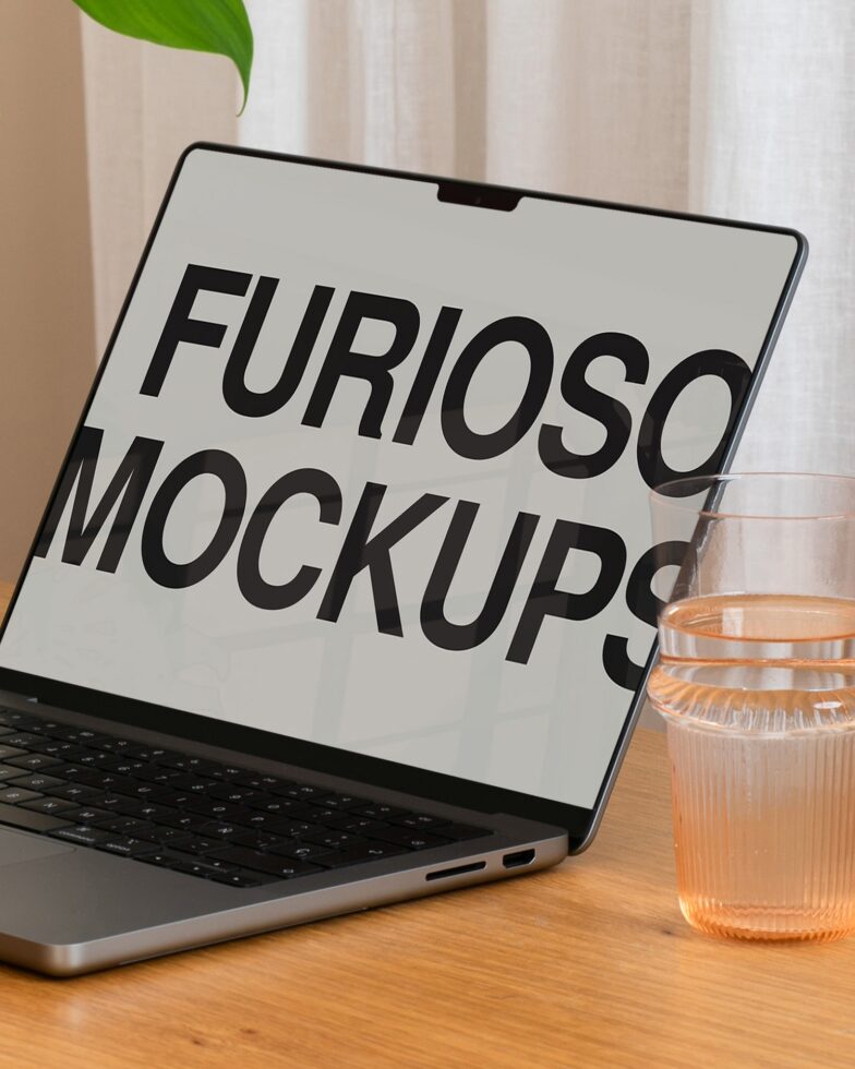 Angled laptop screen mockup next to water glass on minimal desk setting