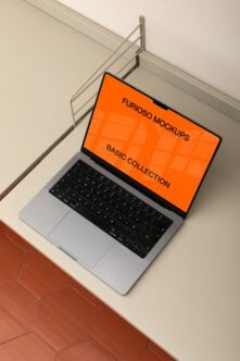 Open laptop showing orange screen mockup on minimal desk setup with wire organizer