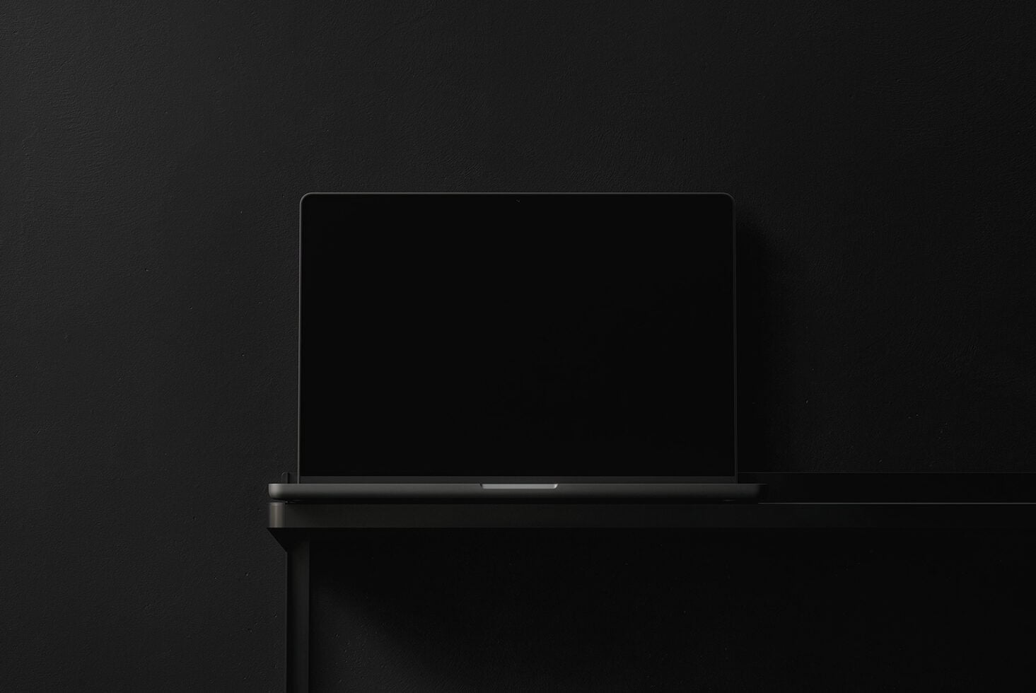 Closed laptop with dark screen angled against black studio backdrop