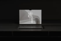 Laptop displaying abstract curved form design mockup on black surface setup