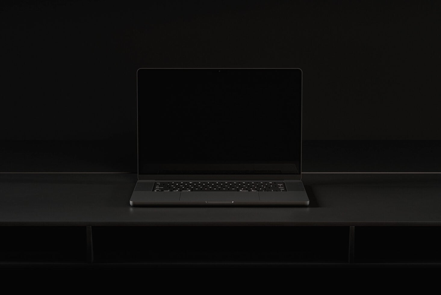 Dark laptop sitting on black desk with blank screen mockup in studio lighting