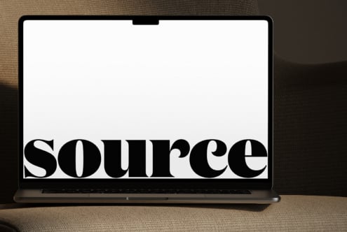 Laptop on neutral fabric with oversized serif letterforms displayed