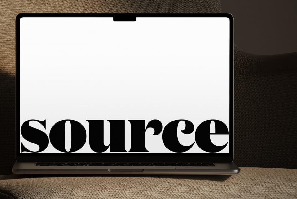Laptop on neutral fabric with oversized serif letterforms displayed