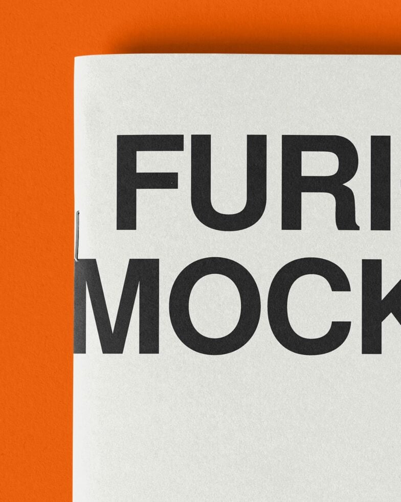 Close up of white paper with big chunky black letters against bright orange background