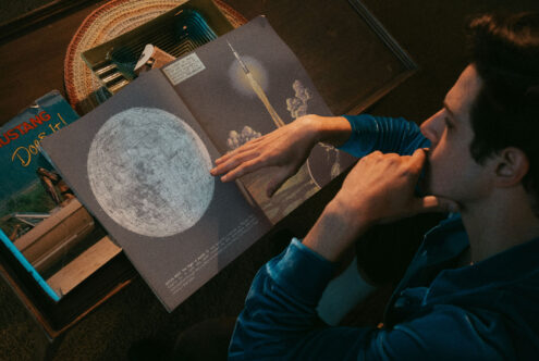 Magazine layout featuring moon map illustration with hands flipping pages