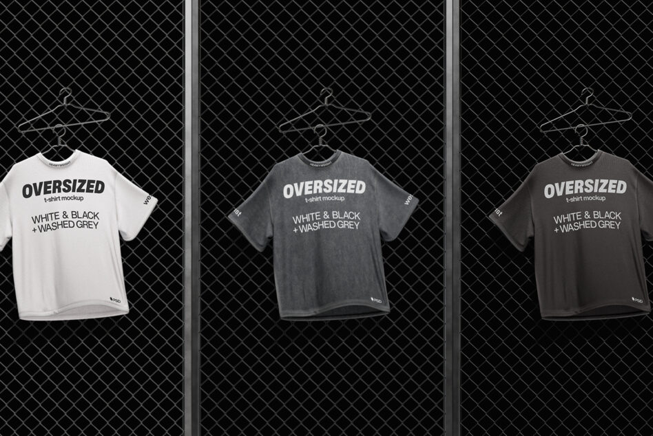 Oversized t-shirt mockup in white, charcoal, plus dark grey on hangers against chain-link wall
