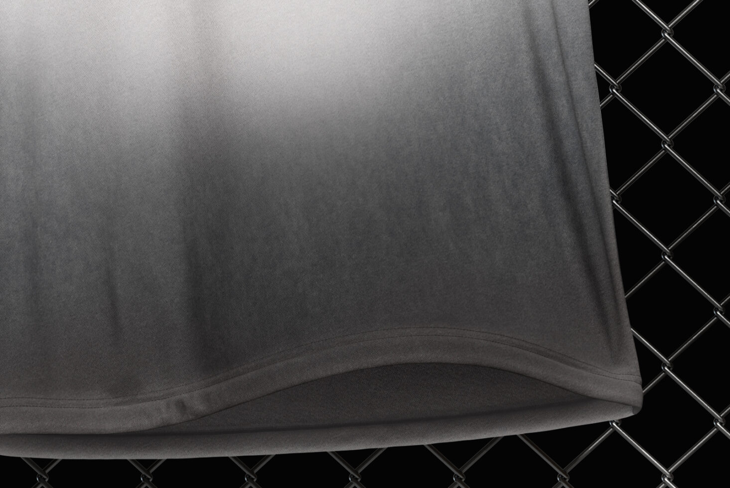 Oversized tee fabric detail showing hem fold against chain-link texture