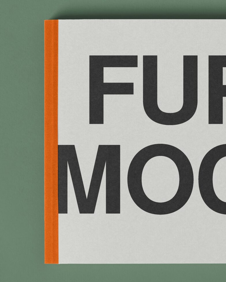 Magazine or book cover close-up with orange spine, bold sans-serif text on cream
