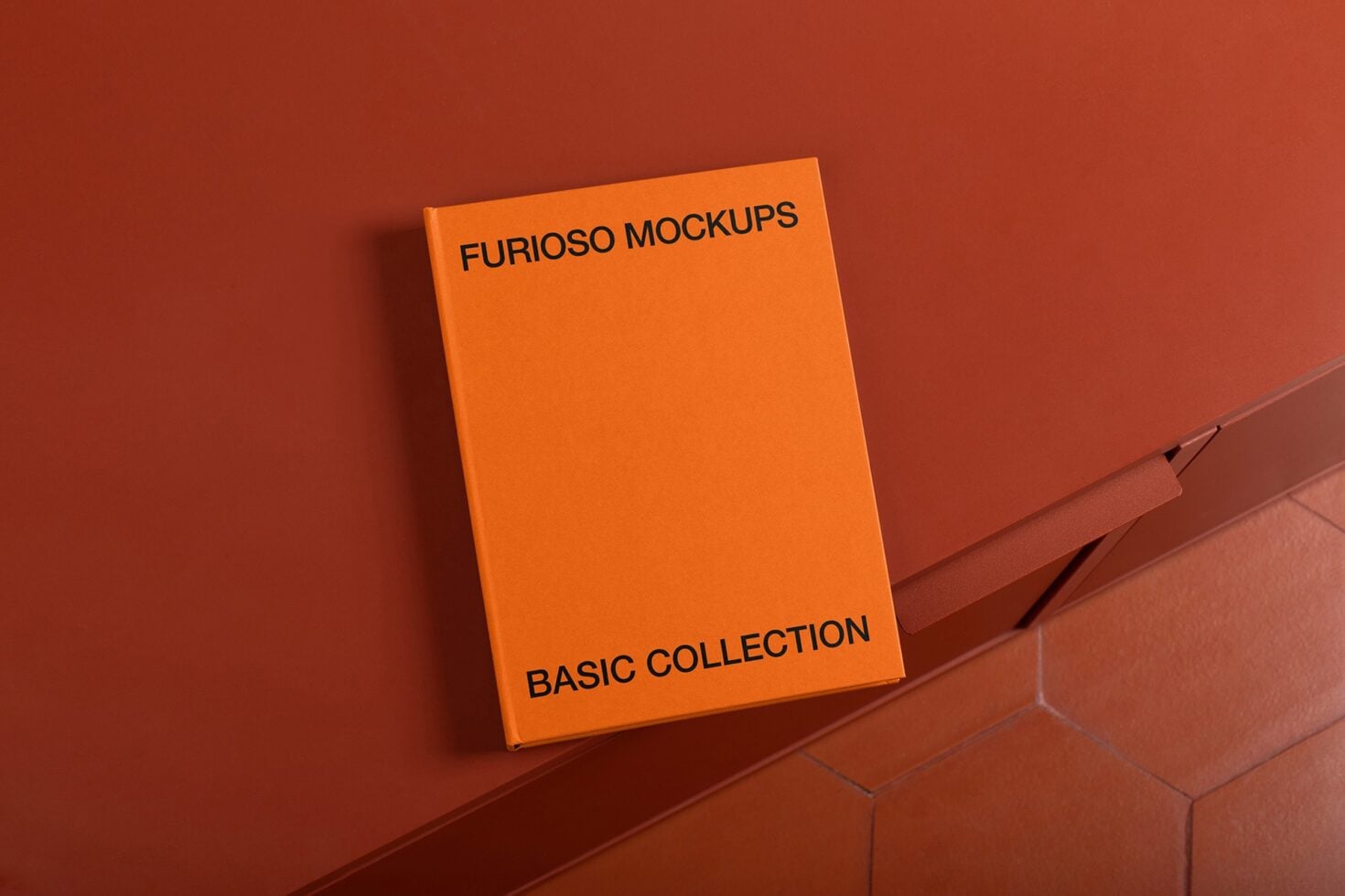 Bright orange hardcover book mockup on terracotta surface with textured tiles