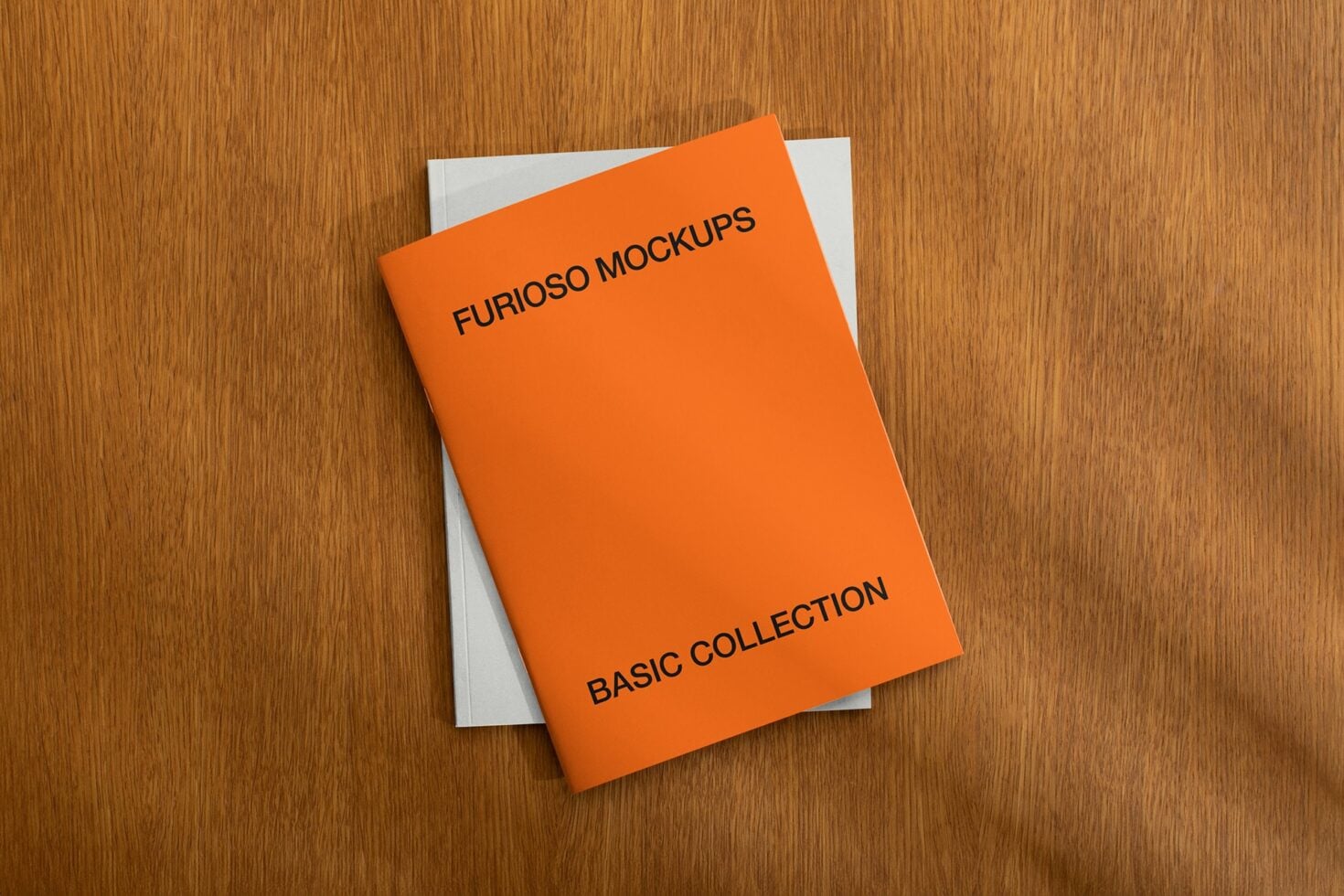 Bright orange softcover booklet on wooden surface with white pages showing
