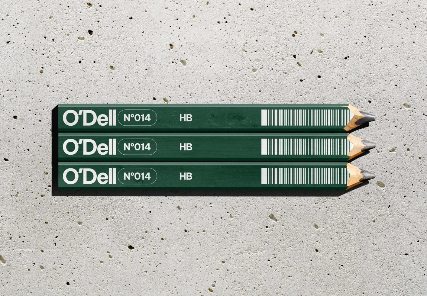 Three O'Dell HB pencils stacked on speckled concrete surface