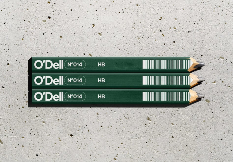 Three O'Dell HB pencils stacked on speckled concrete surface