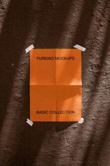 Orange poster taped to dark brick wall, white tape corners mockup