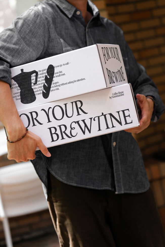 White branded box with coffee house design held in hands showing front branding