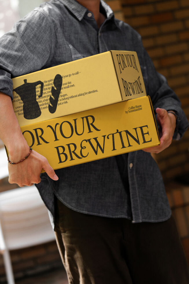 Yellow branded box with coffee house design held in hands showing front branding