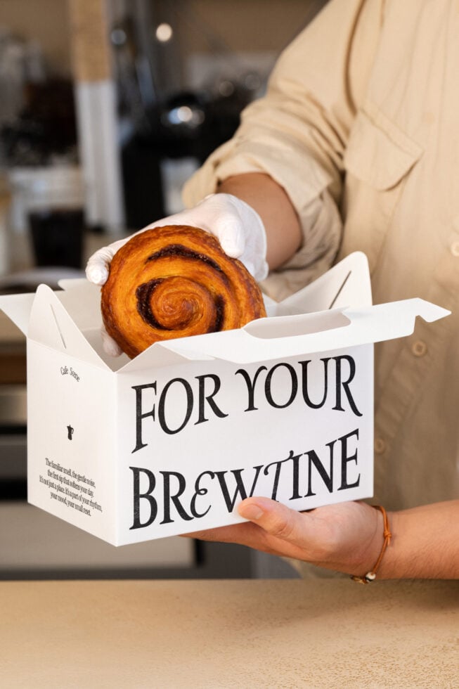 Cream bakery box mockup displaying fresh pastry in white gloves, text overlay