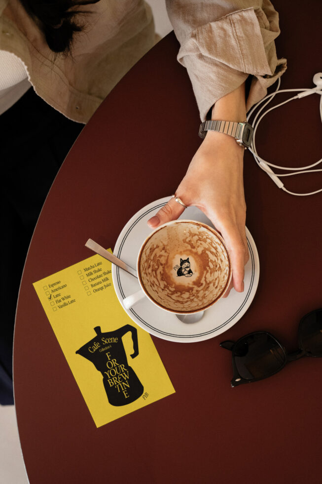 Overhead coffee shot with yellow flyer mockup next to latte cup on table