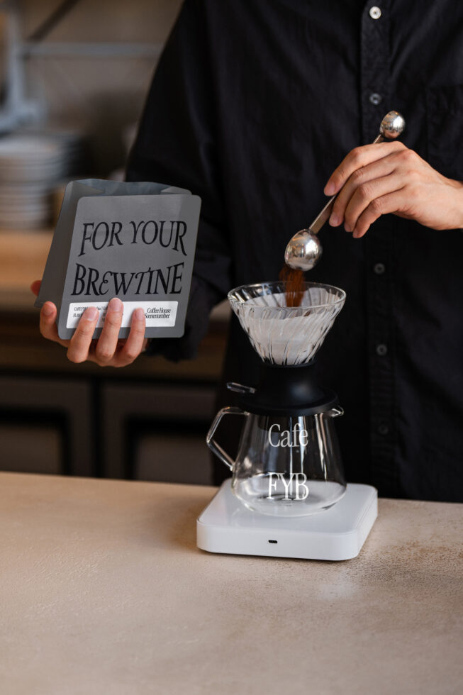 Coffee pour-over setup with white bag mockup held beside brewing glass vessel