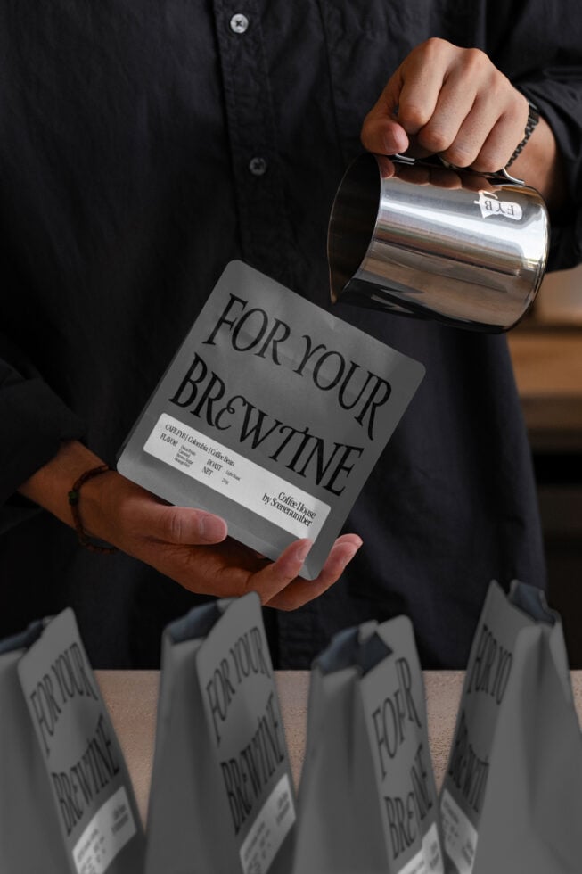 Dark gray coffee bag mockup held in hand with metal pitcher pouring above