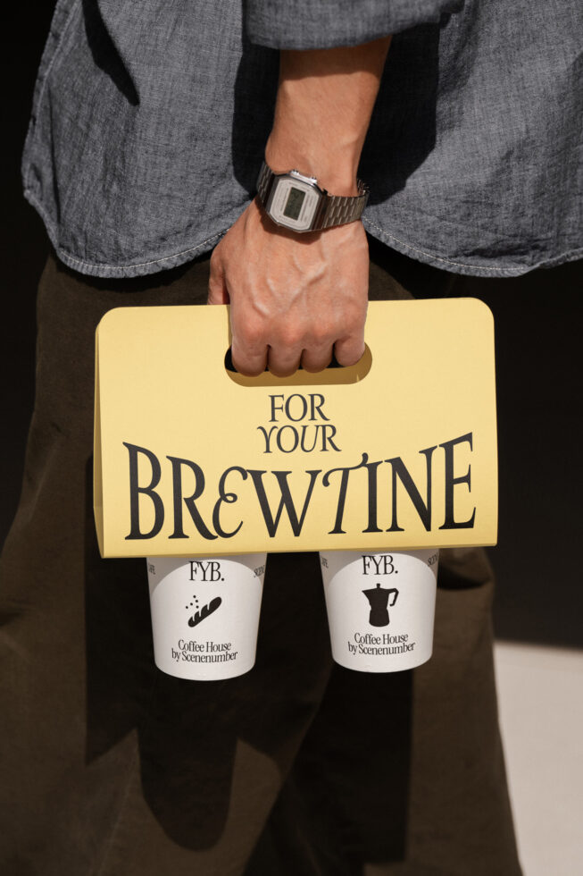 Man holding yellow paper bag with coffee cups below, retro digital watch visible