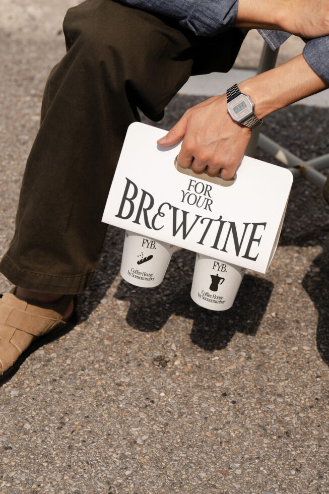 White coffee sleeve with two cups held in casual outdoor setting