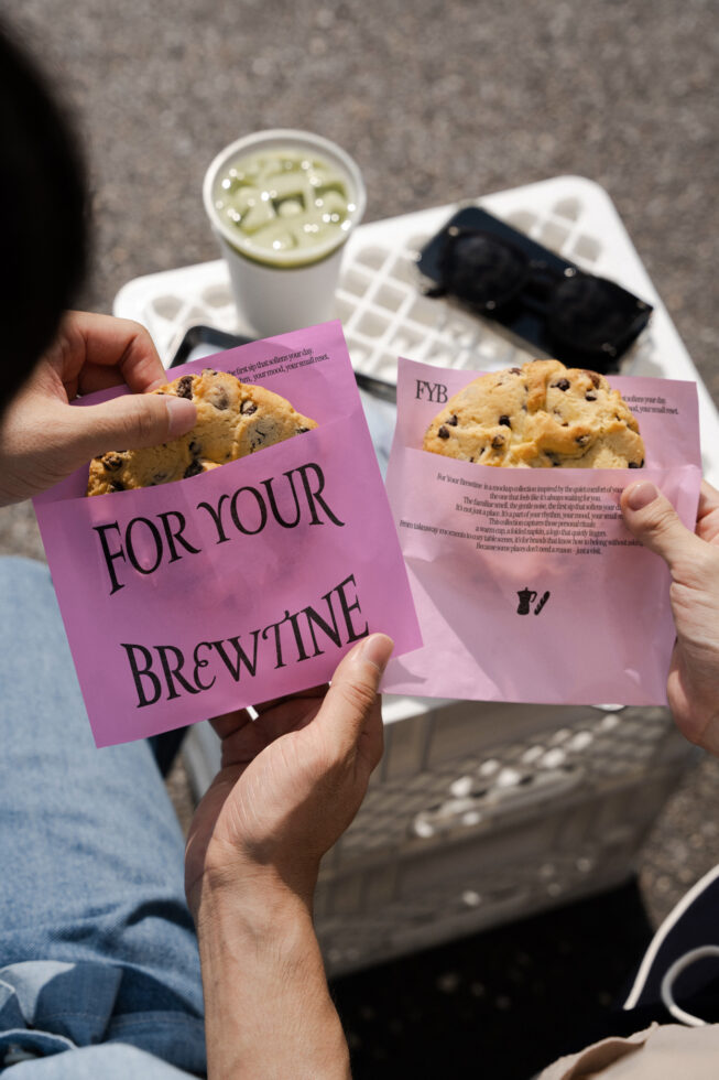Two hands hold paper bags with cookies showing For Your Brewtine text