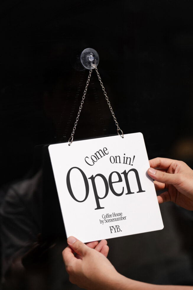 White square sign hanging on chain reads Come on in Open for coffee