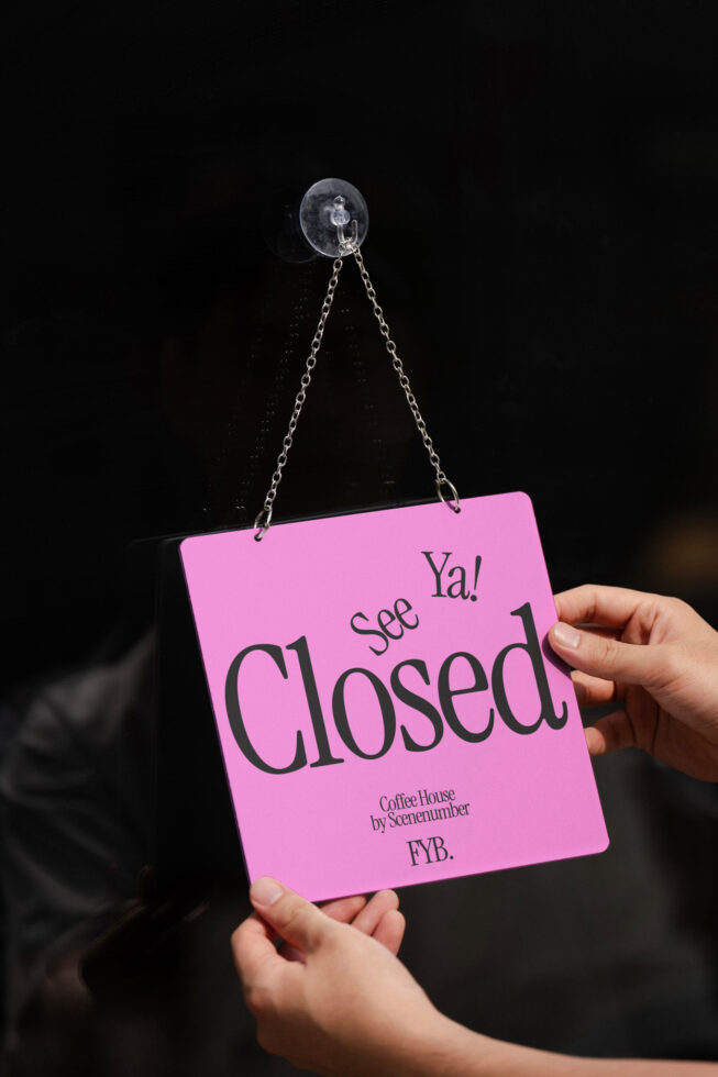 Bright pink hanging sign says See Ya Closed against black background
